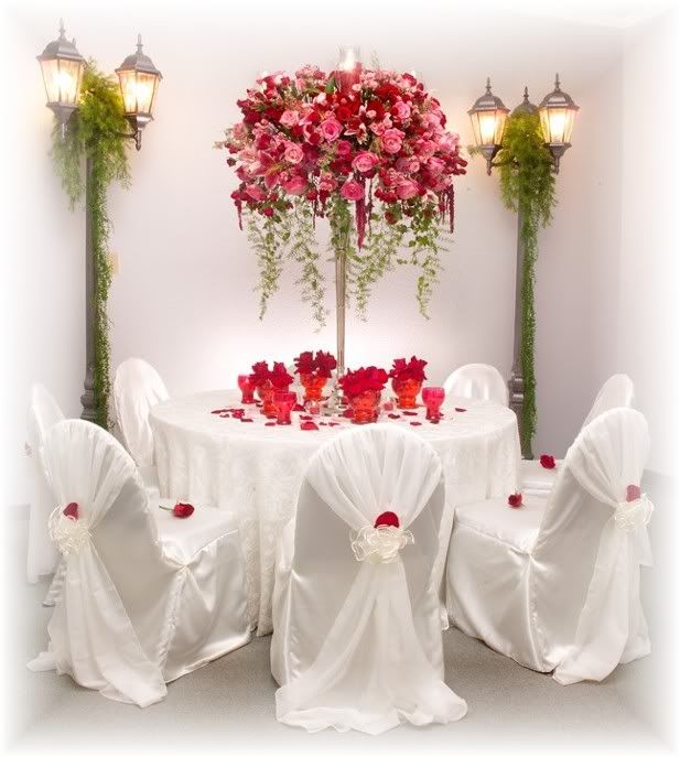White tablecloth on round table Centerpiece is tall and narrow with bouquet 